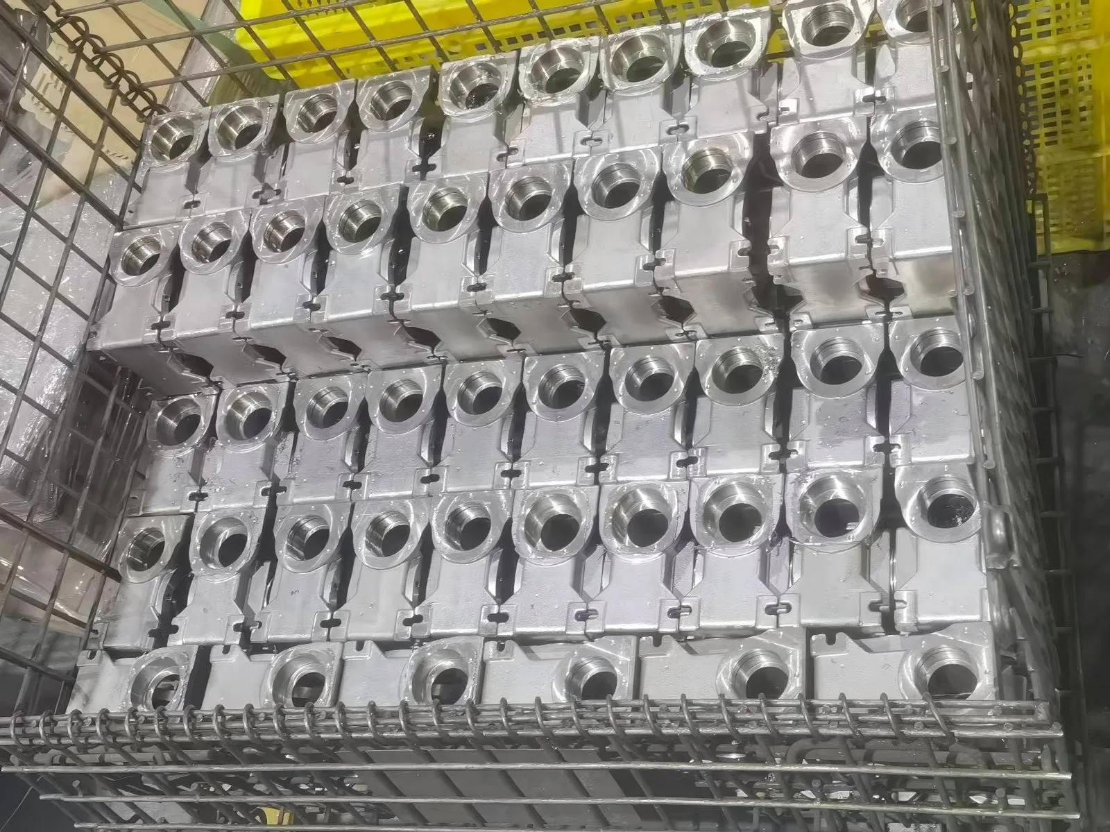Bulk inventory of CNC machined stainless steel gearbox housings in wire baskets, ready for rapid assembly in hygienic washdown environments.